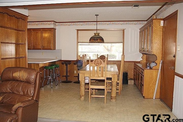 dining area featuring ornamental molding and wooden walls