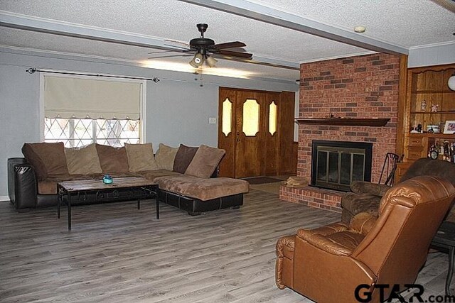 living room featuring a fireplace, wood-type flooring, a textured ceiling, and ceiling fan