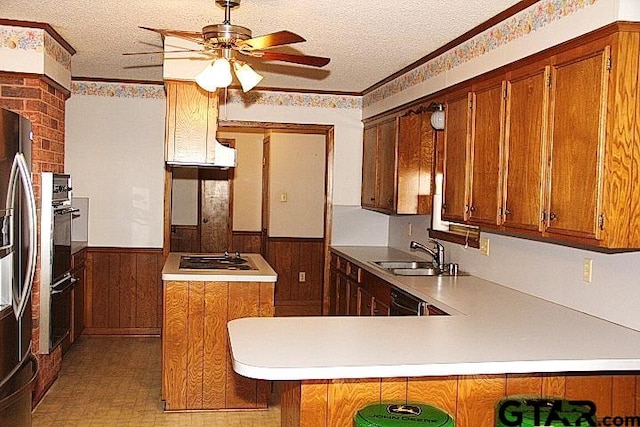 kitchen with gas stovetop, a textured ceiling, wood walls, sink, and kitchen peninsula