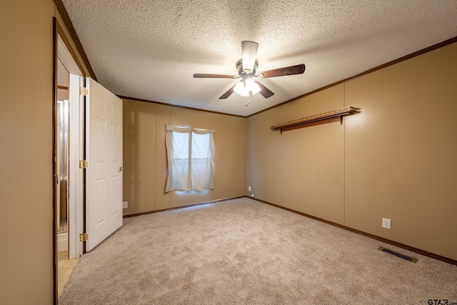 unfurnished bedroom featuring a textured ceiling, light colored carpet, ornamental molding, and ceiling fan