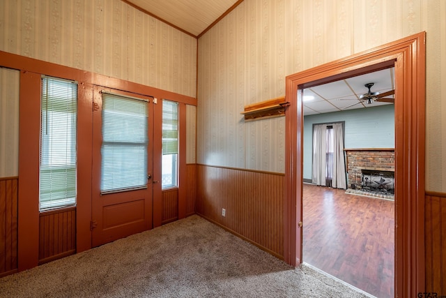 doorway to outside with wood walls, hardwood / wood-style floors, ceiling fan, and a fireplace