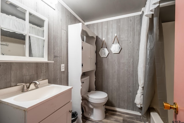 full bathroom with shower / bath combo, wood-type flooring, toilet, wood walls, and vanity