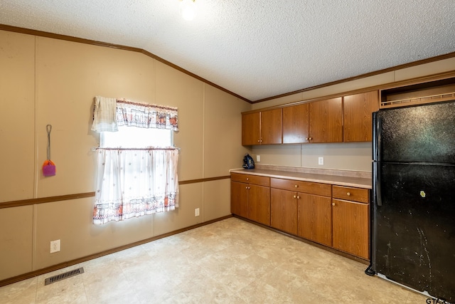 kitchen featuring black refrigerator, lofted ceiling, a textured ceiling, and ornamental molding