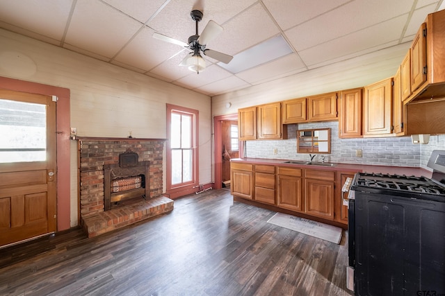 kitchen featuring dark wood-type flooring, black range with gas cooktop, a paneled ceiling, and sink