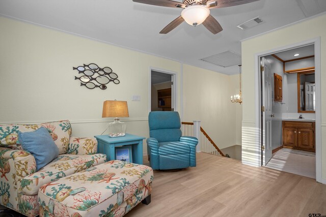 living area with crown molding, sink, ceiling fan with notable chandelier, and light wood-type flooring