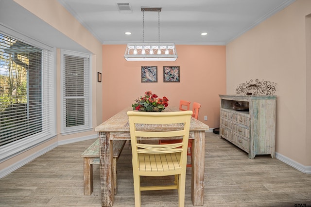 dining space with light hardwood / wood-style floors and crown molding