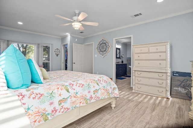 bedroom featuring light wood-type flooring, ensuite bathroom, ceiling fan, and crown molding
