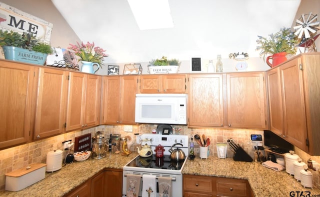 2333 Baretta Dr, Mesquite, TX 75181 - kitchen with white appliances, decorative backsplash, light stone counters, vaulted ceiling, and a skylight