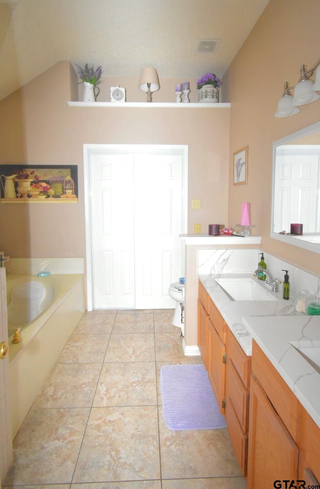 2333 Baretta Dr, Mesquite, TX 75181 - bathroom featuring a garden tub, tile patterned floors, vanity, toilet, and vaulted ceiling