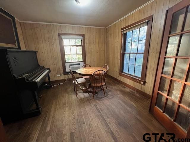dining space with baseboards, cooling unit, crown molding, wood walls, and wood finished floors