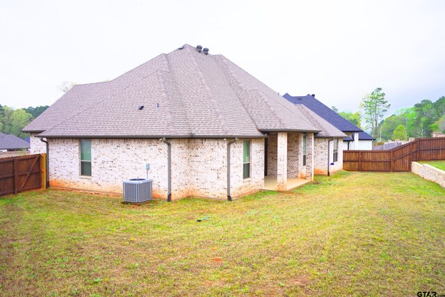 back of property with a fenced backyard, cooling unit, brick siding, and a yard