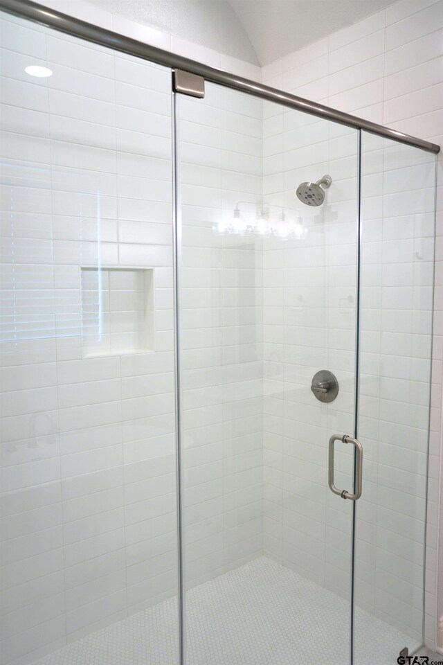 full bathroom with vaulted ceiling and a shower stall