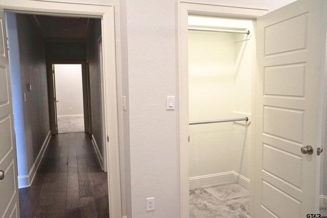 corridor featuring baseboards and dark wood-style flooring