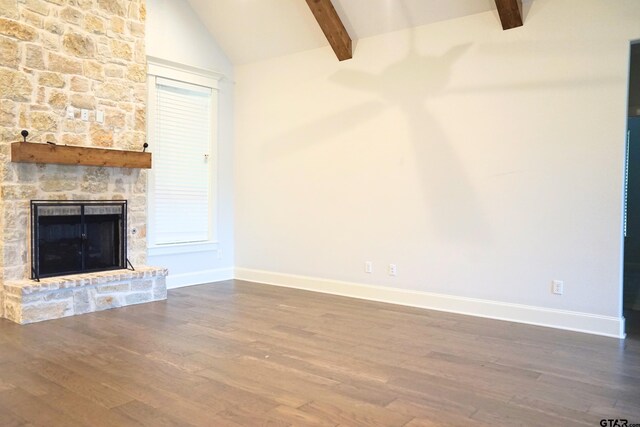 unfurnished living room with baseboards, dark wood-style floors, vaulted ceiling with beams, and a stone fireplace