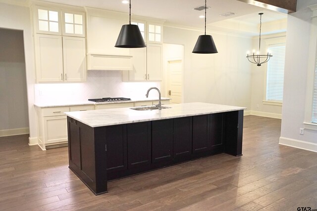 kitchen with white cabinetry, a center island with sink, a notable chandelier, and dark wood finished floors