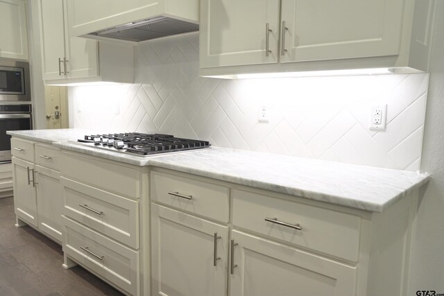kitchen with tasteful backsplash, stainless steel appliances, dark wood finished floors, extractor fan, and light stone countertops