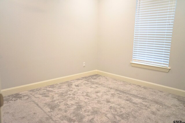 carpeted spare room featuring baseboards