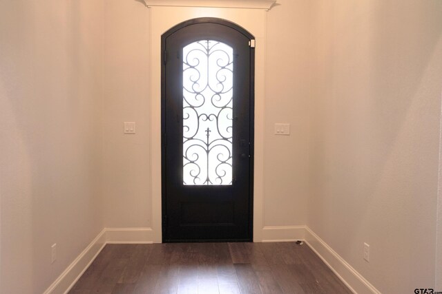 entryway featuring dark wood finished floors, baseboards, and arched walkways