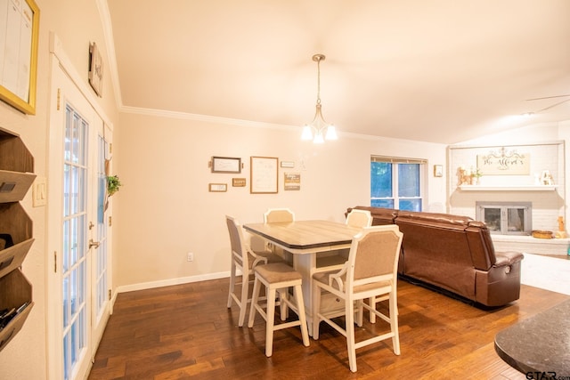 dining room featuring ornamental molding, a glass covered fireplace, a chandelier, and dark wood finished floors