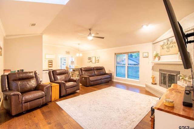 living room with a fireplace, visible vents, vaulted ceiling, dark wood-style floors, and crown molding