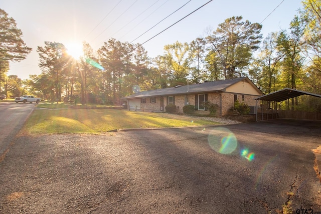 ranch-style house featuring driveway, brick siding, and a detached carport