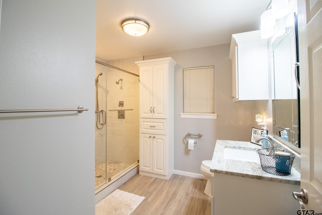 full bathroom with a closet, toilet, a stall shower, vanity, and wood finished floors