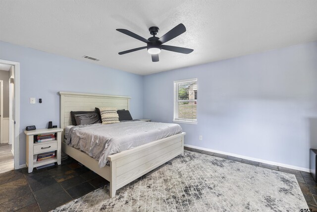 14553 Stone Creek Dr, Tyler, TX 75709 - bedroom featuring stone tile floors, a textured ceiling, baseboards, ceiling fan, and visible vents