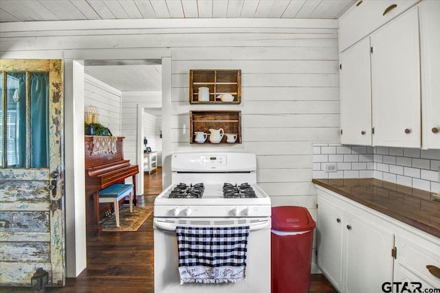13926 State Highway 64e, Tyler, TX 75707 - kitchen with white gas range oven, dark countertops, white cabinets, wood walls, and dark wood-style flooring