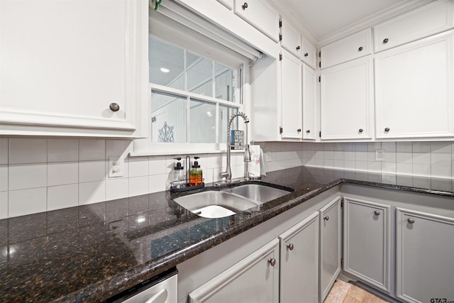 kitchen with white cabinets, dark stone countertops, sink, and decorative backsplash