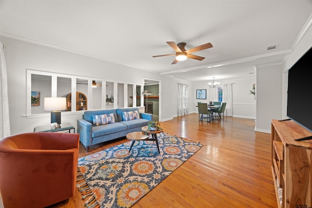 living room with ornamental molding, ceiling fan with notable chandelier, and hardwood / wood-style flooring