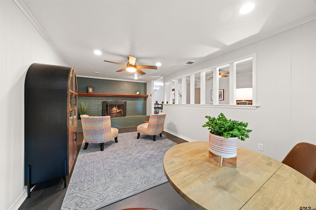 interior space featuring ceiling fan, concrete floors, crown molding, and a brick fireplace