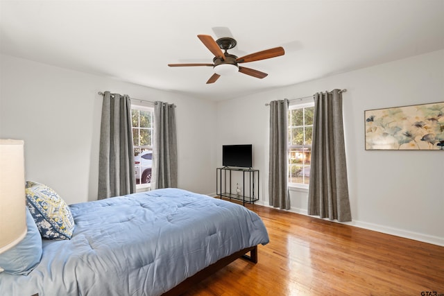 bedroom featuring hardwood / wood-style flooring, ceiling fan, and multiple windows