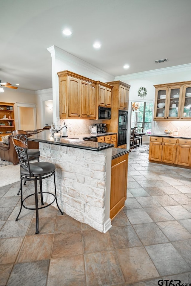 kitchen featuring sink, black appliances, a breakfast bar, kitchen peninsula, and backsplash