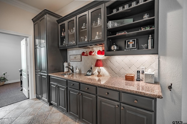 bar featuring light stone countertops, sink, backsplash, and crown molding