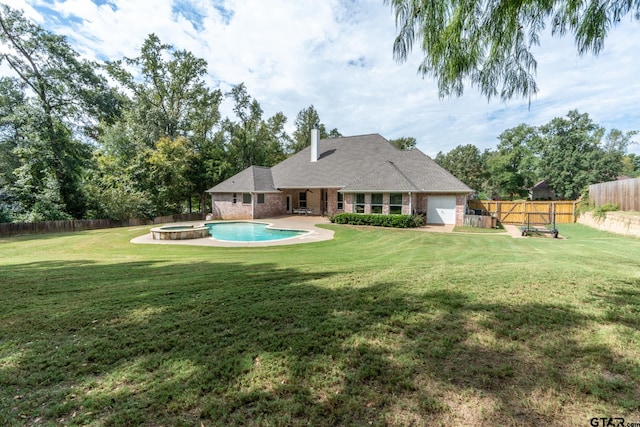 rear view of house featuring a swimming pool with hot tub, a patio, and a yard