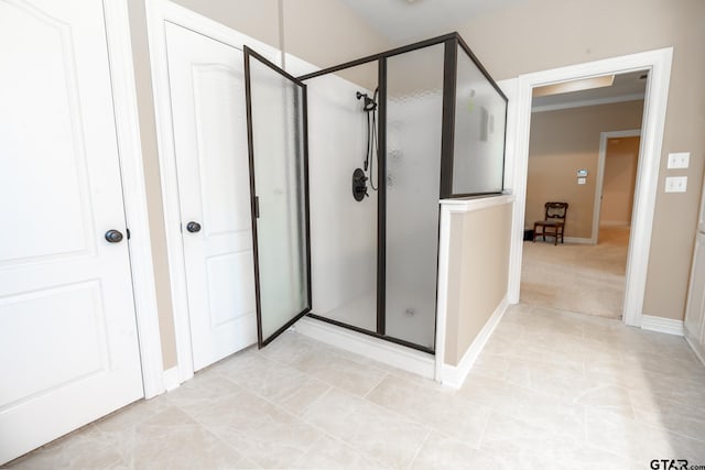 bathroom with tile patterned floors, crown molding, and a shower with shower door