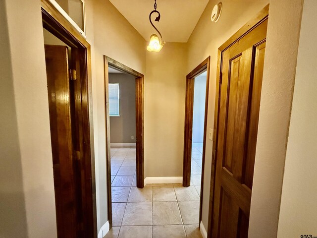 hall featuring light tile patterned flooring and baseboards