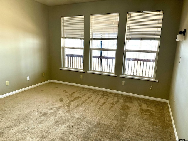 carpeted empty room featuring baseboards