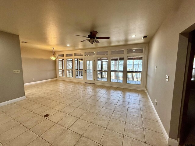 unfurnished living room featuring light tile patterned flooring, a ceiling fan, visible vents, and baseboards