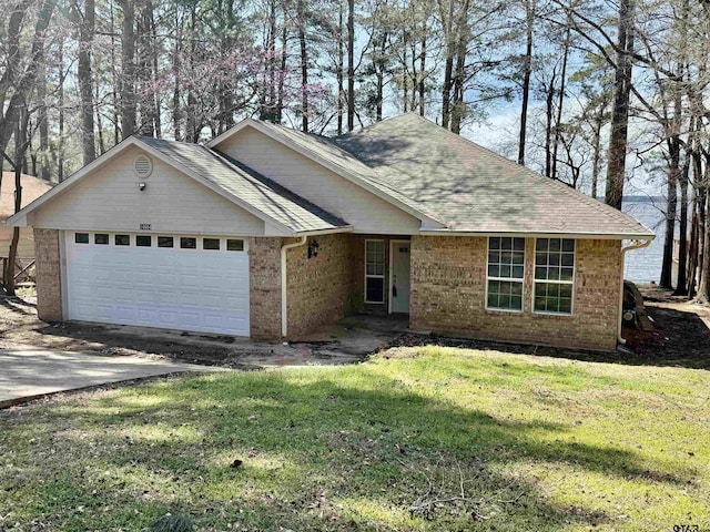 ranch-style home with a front yard, driveway, roof with shingles, an attached garage, and brick siding