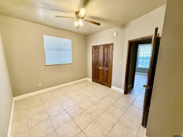 unfurnished bedroom featuring light tile patterned floors, baseboards, and ceiling fan