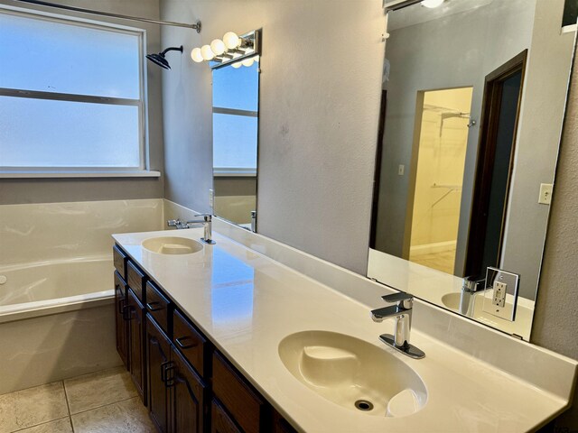 full bathroom with tile patterned floors, double vanity, a garden tub, and a sink