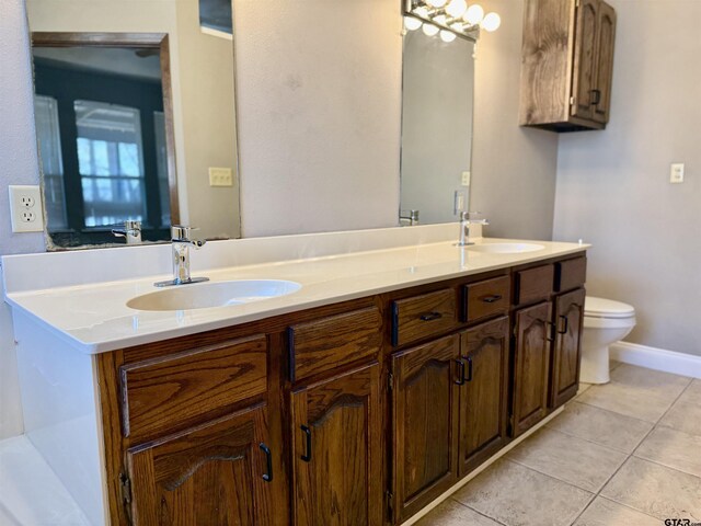 bathroom featuring tile patterned flooring, double vanity, toilet, and a sink