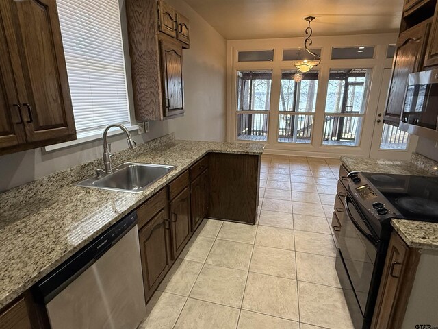 kitchen with pendant lighting, a sink, stainless steel appliances, dark brown cabinetry, and light tile patterned floors