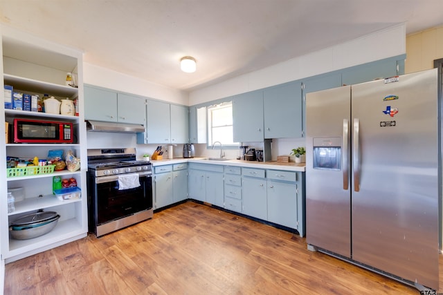 kitchen with appliances with stainless steel finishes, sink, blue cabinetry, and light hardwood / wood-style flooring