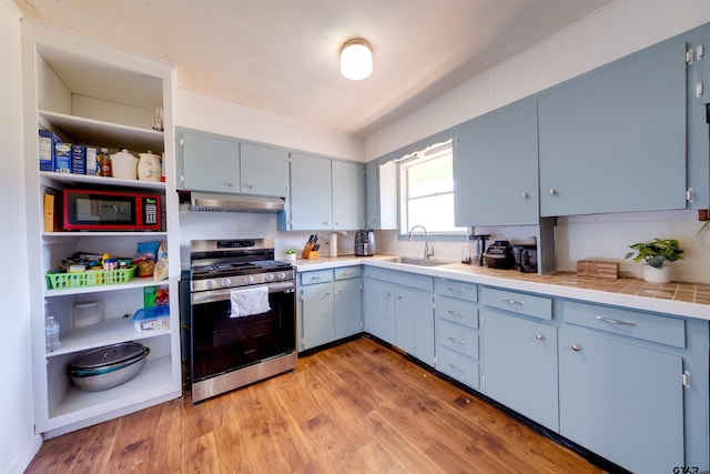 kitchen featuring light hardwood / wood-style flooring, sink, stainless steel gas range, and blue cabinetry