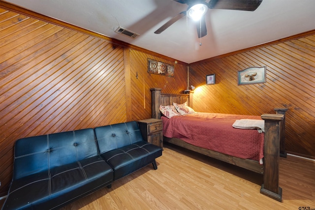 bedroom with hardwood / wood-style flooring, ornamental molding, ceiling fan, and wood walls