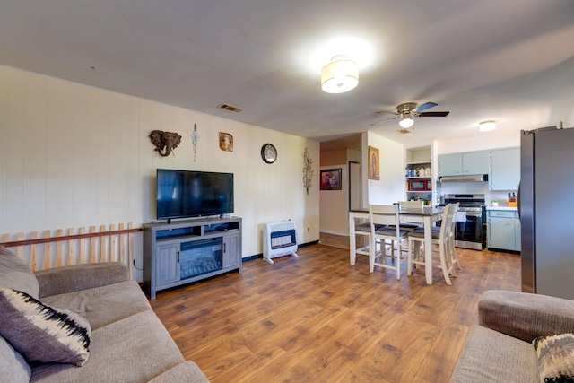 living room with hardwood / wood-style flooring, ceiling fan, and heating unit