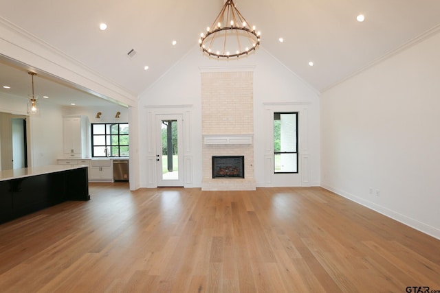 16511 Cooper Way, Tyler, TX 75703 - unfurnished living room with a chandelier, high vaulted ceiling, a brick fireplace, light wood-style floors, and baseboards