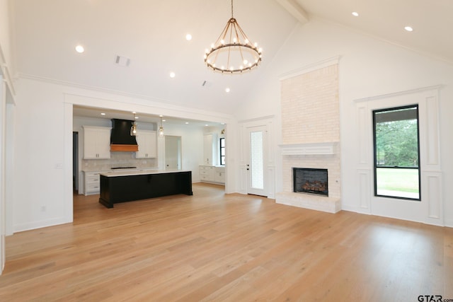 16511 Cooper Way, Tyler, TX 75703 - unfurnished living room featuring high vaulted ceiling, a chandelier, beamed ceiling, light wood finished floors, and a brick fireplace